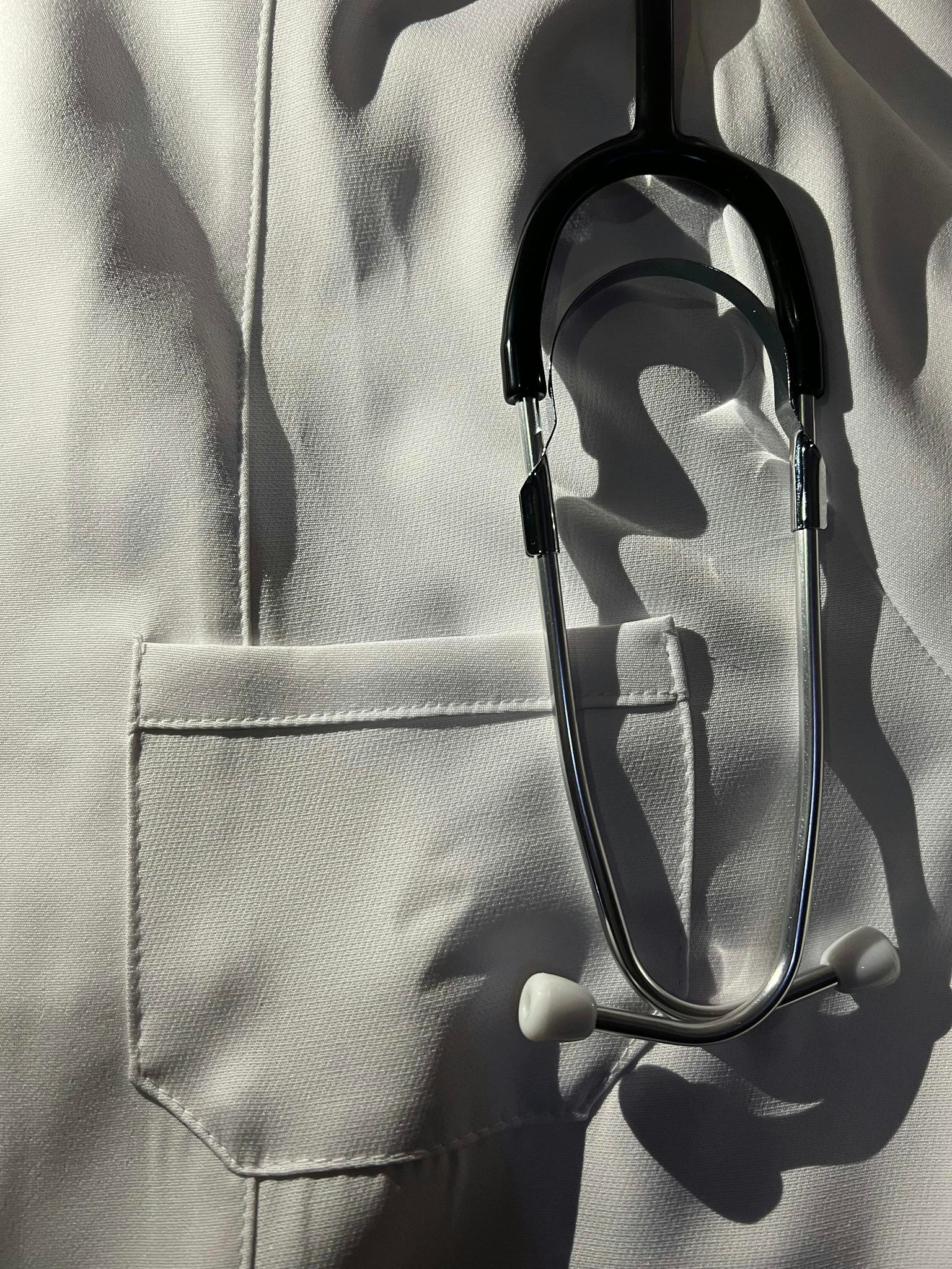 Detailed image of a stethoscope hanging on a medical professional's white coat, symbolizing healthcare.